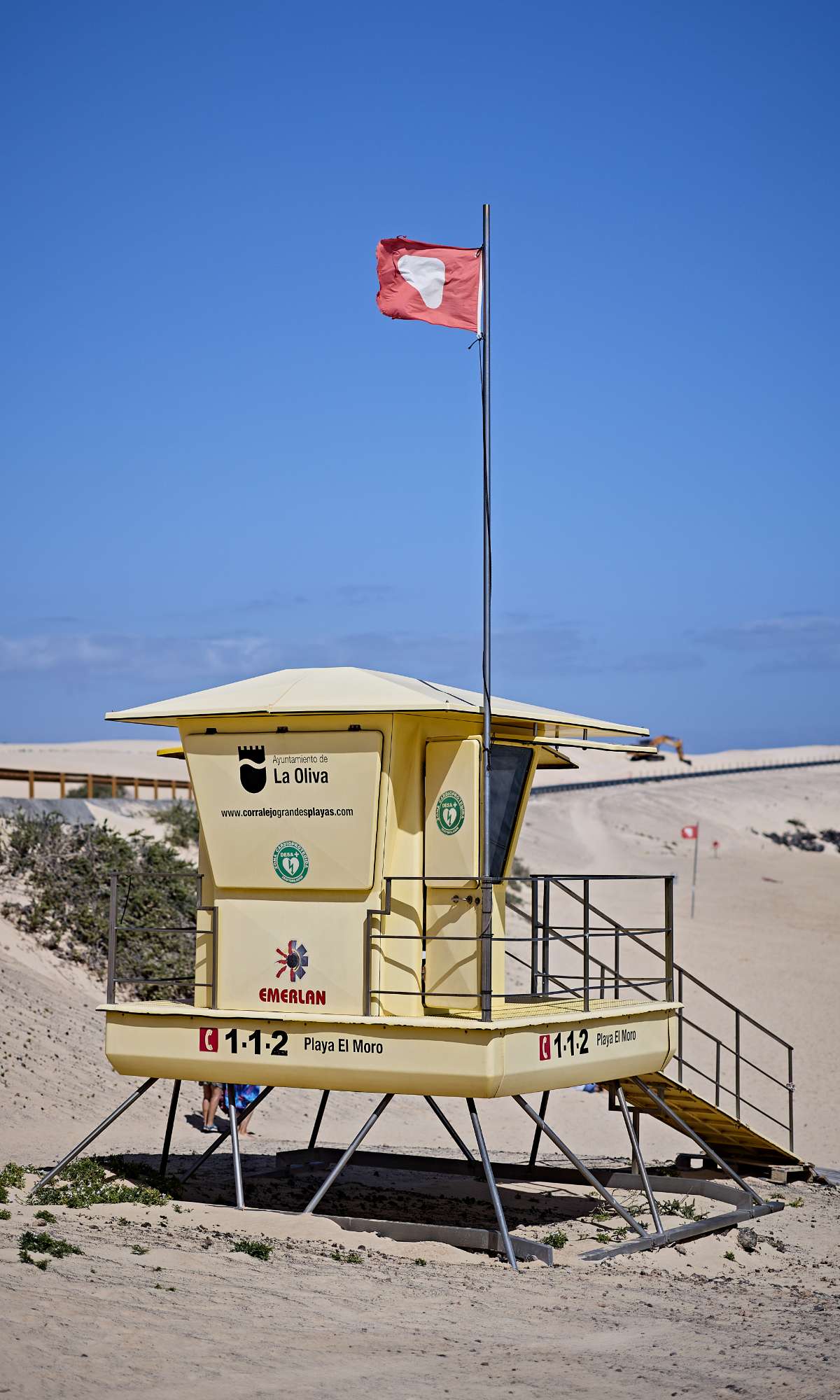 Poste de secours sur une plage de sable avec drapeau rouge et le texte 1-1-2 Playa El Moro.