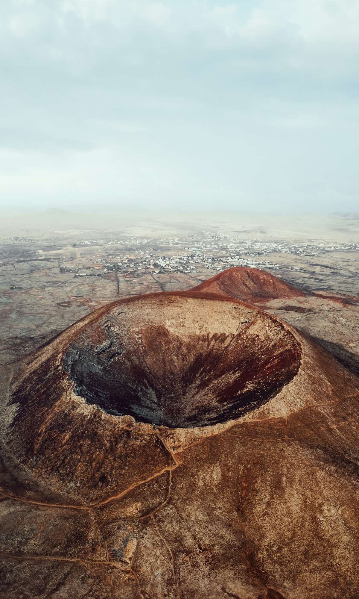 Vue aérienne d’un grand cratère volcanique dans un paysage aride.