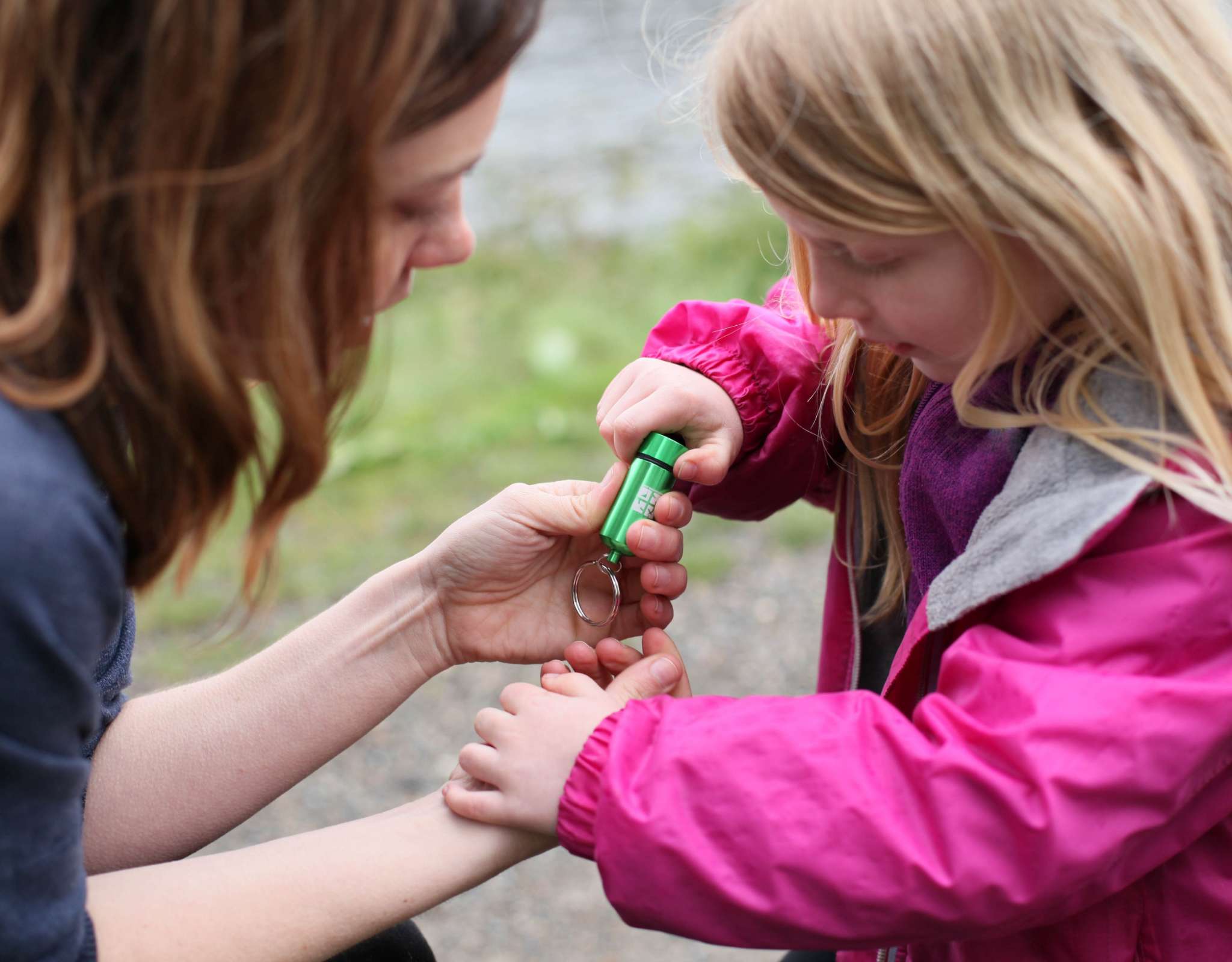 Kind en volwassene openen een groene geocachekoker buiten