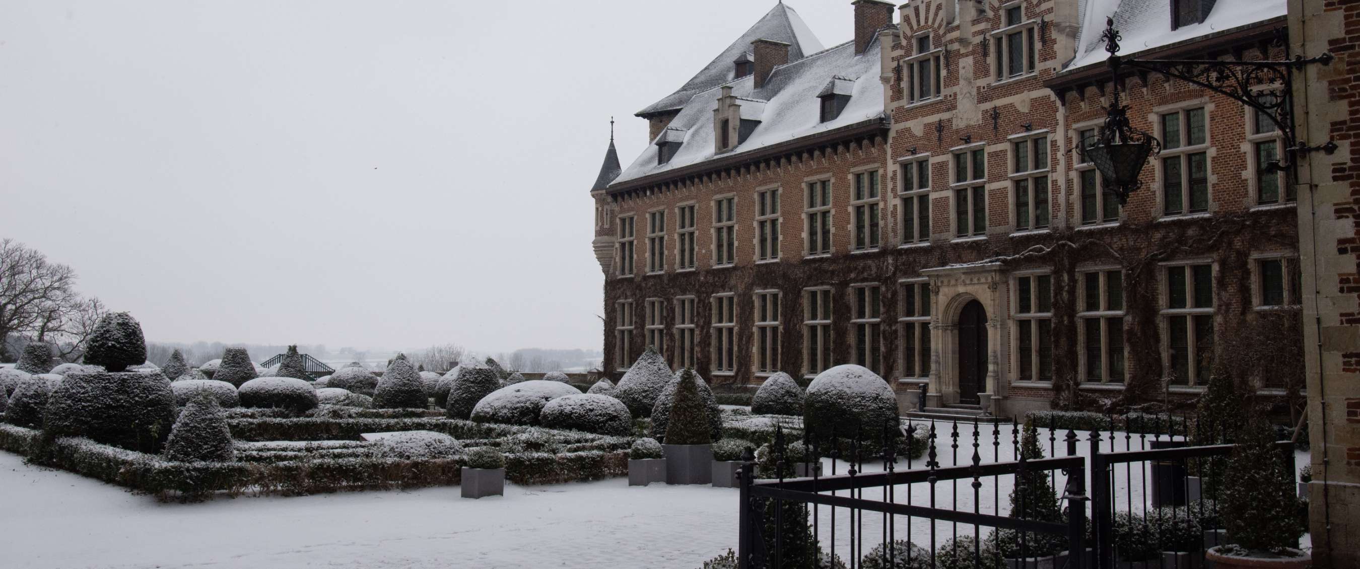 Jardin de château couvert de neige à côté d’un édifice monumental