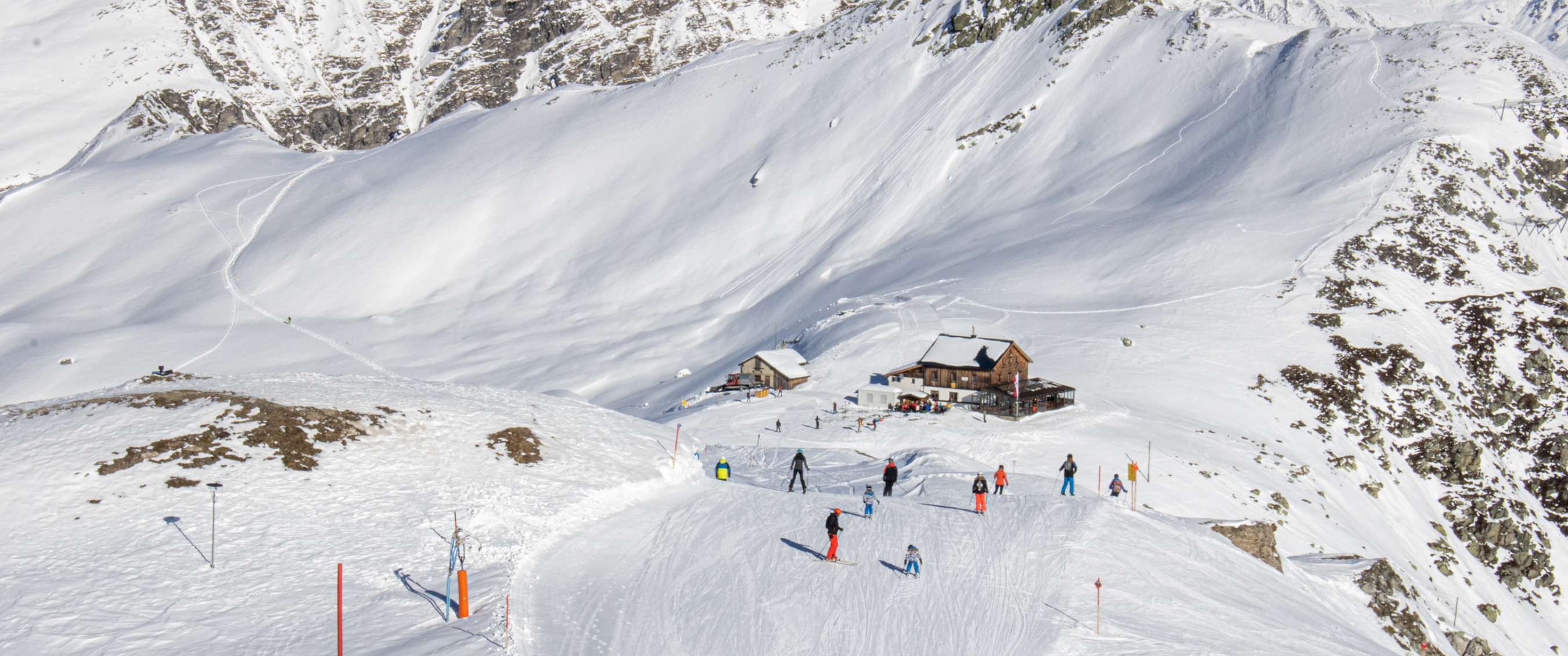 Un flanc de montagne enneigé avec quelques refuges de ski et des skieurs à Zillertal.