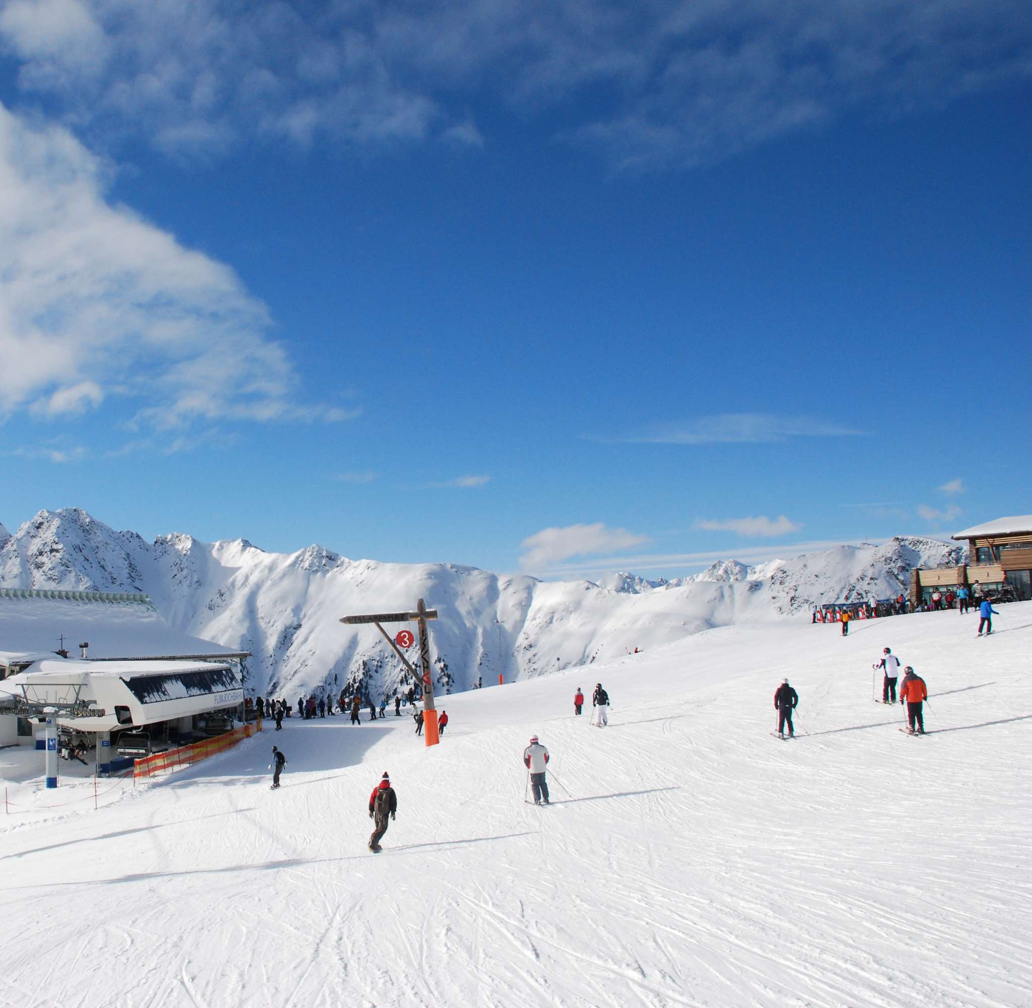 Une station de ski avec un grand bâtiment et des skieurs sur une large pente enneigée à Ischgl.